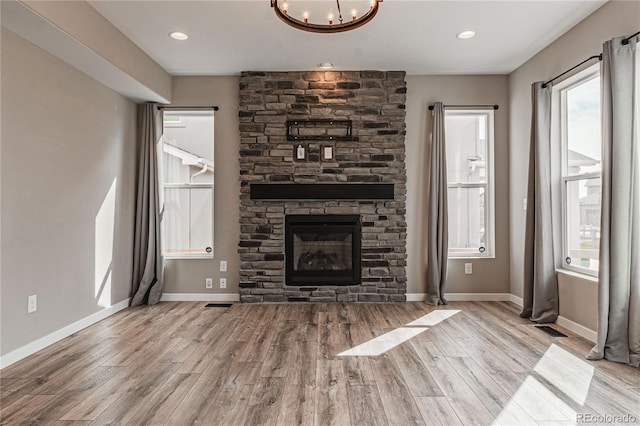 unfurnished living room featuring a notable chandelier, a fireplace, and light hardwood / wood-style floors