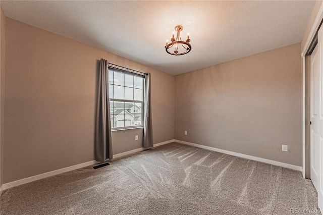 carpeted empty room with an inviting chandelier