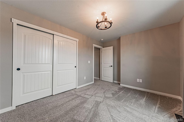 unfurnished bedroom with light colored carpet, an inviting chandelier, and a closet