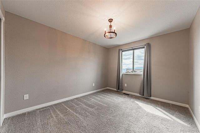 carpeted spare room with an inviting chandelier