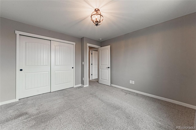 unfurnished bedroom with carpet flooring, an inviting chandelier, and a closet