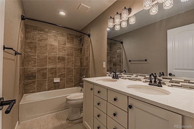 full bathroom featuring tile patterned floors, toilet, tiled shower / bath, vanity, and decorative backsplash