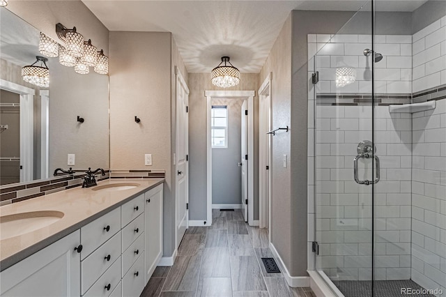 bathroom featuring an inviting chandelier, vanity, and an enclosed shower