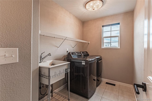 laundry room featuring sink, washer and dryer, and light tile patterned flooring