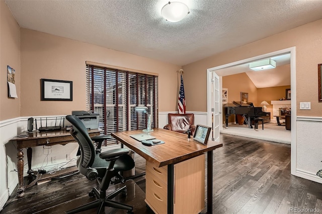 home office featuring lofted ceiling, dark wood-type flooring, and a textured ceiling