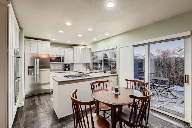 kitchen featuring a center island, dark wood-type flooring, tasteful backsplash, white cabinets, and appliances with stainless steel finishes