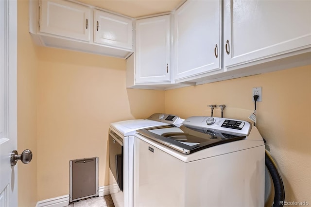 laundry room featuring washer and clothes dryer, light tile patterned flooring, and cabinets