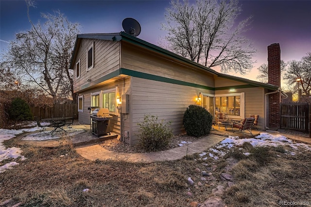 back house at dusk with a patio area