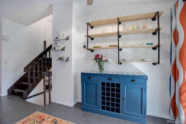 bar with stairway, baseboards, and dark tile patterned floors