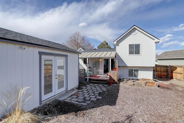 rear view of property with french doors, roof with shingles, a vegetable garden, fence, and a deck