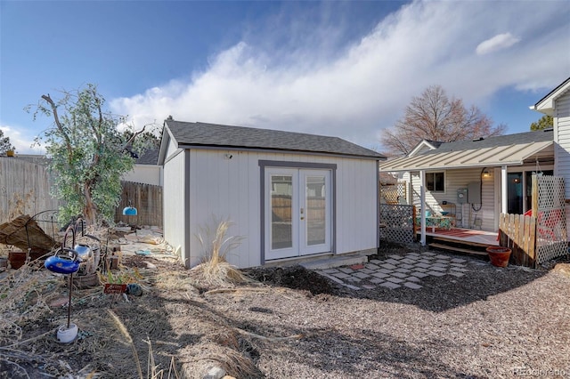 rear view of house featuring a shingled roof, fence, a deck, and an outdoor structure