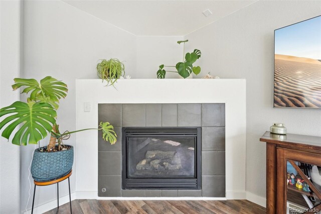 details featuring a tile fireplace, baseboards, and wood finished floors