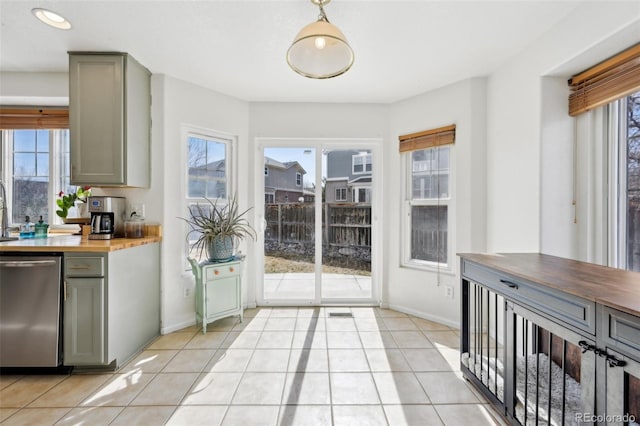 interior space featuring light tile patterned floors, stainless steel dishwasher, gray cabinets, and butcher block counters