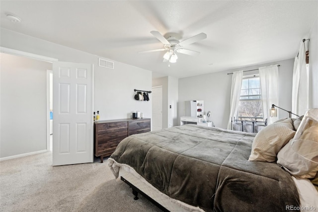 bedroom with baseboards, light colored carpet, visible vents, and ceiling fan