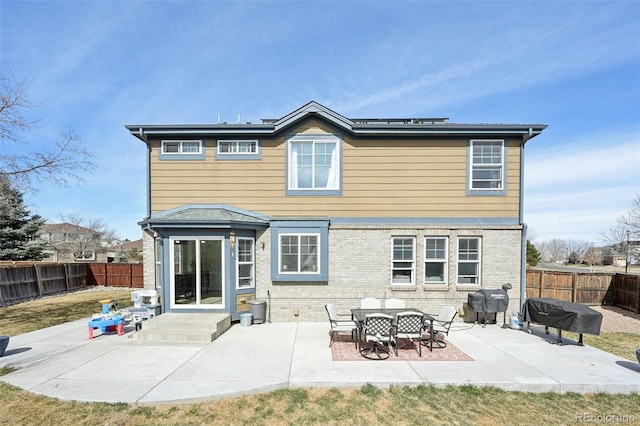 rear view of house featuring a patio area, brick siding, and a fenced backyard