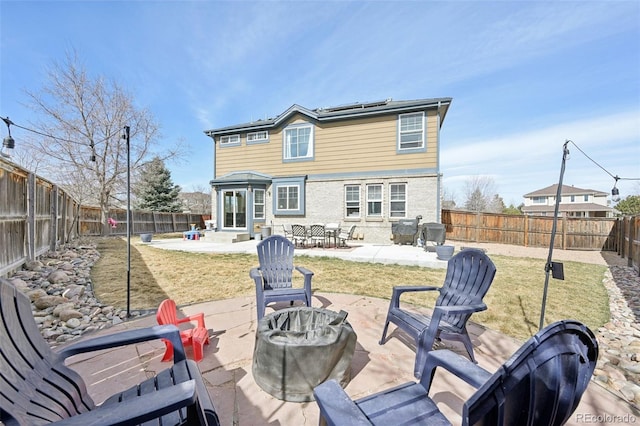 rear view of house with entry steps, a patio area, a fenced backyard, and solar panels