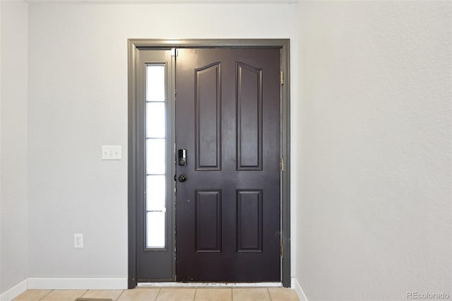 entrance foyer featuring baseboards, plenty of natural light, and light tile patterned flooring