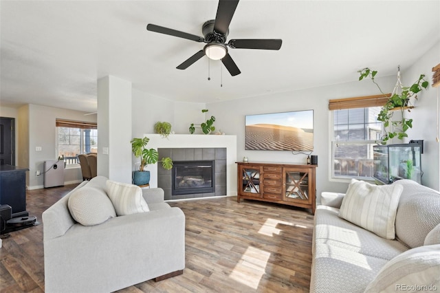 living room featuring a tiled fireplace, wood finished floors, and a ceiling fan