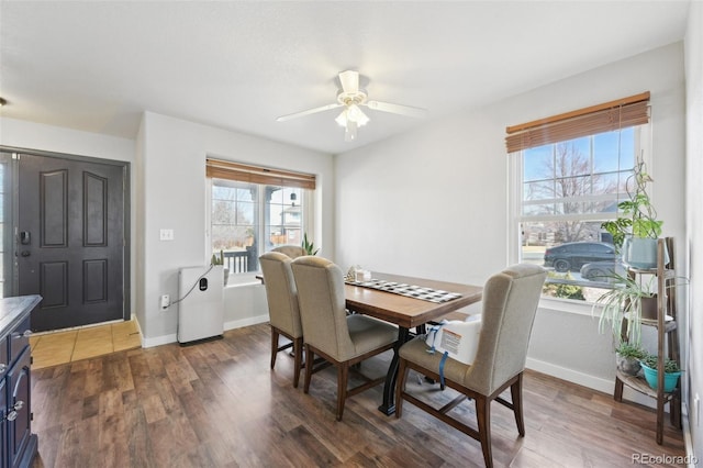 dining area featuring ceiling fan, baseboards, and dark wood finished floors