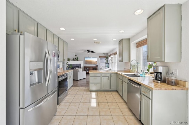 kitchen featuring a sink, appliances with stainless steel finishes, a fireplace, and gray cabinets