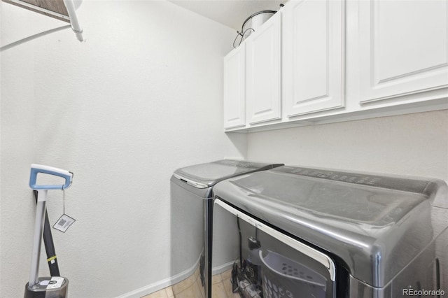 clothes washing area with baseboards, cabinet space, independent washer and dryer, and light tile patterned flooring