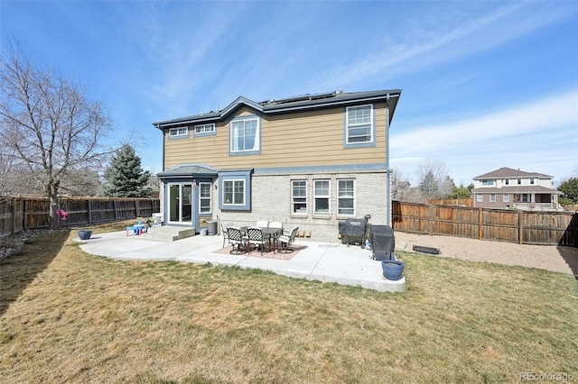 back of house with entry steps, a yard, a patio area, and solar panels