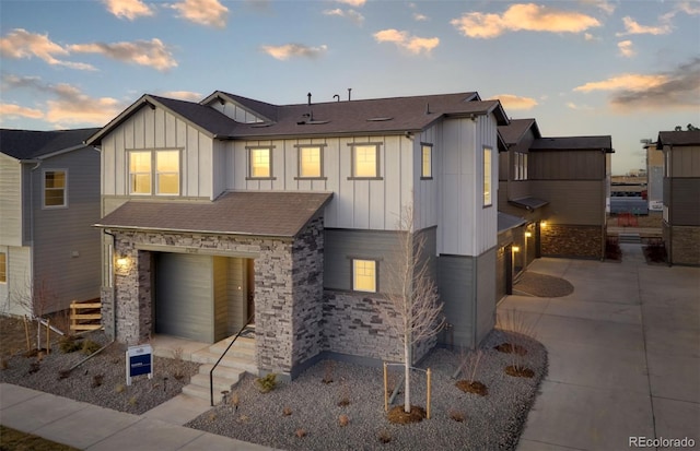 view of front of home featuring concrete driveway, an attached garage, board and batten siding, and stone siding