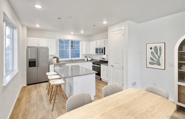 kitchen with visible vents, light wood finished floors, a sink, stainless steel appliances, and a center island