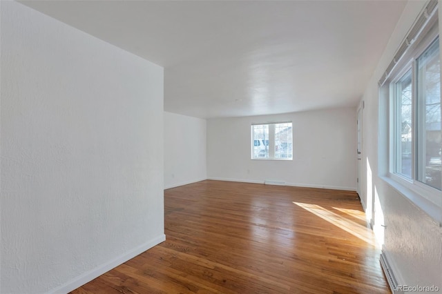 unfurnished room featuring baseboard heating and wood-type flooring