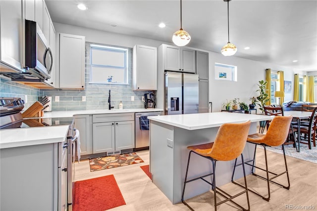 kitchen featuring sink, a center island, hanging light fixtures, gray cabinets, and stainless steel appliances