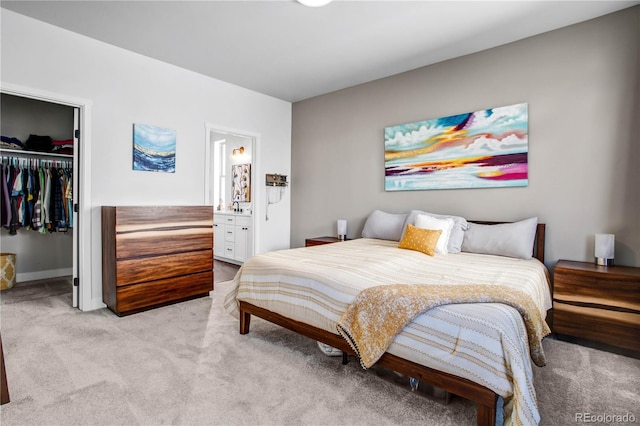 bedroom featuring a walk in closet, connected bathroom, light carpet, and a closet