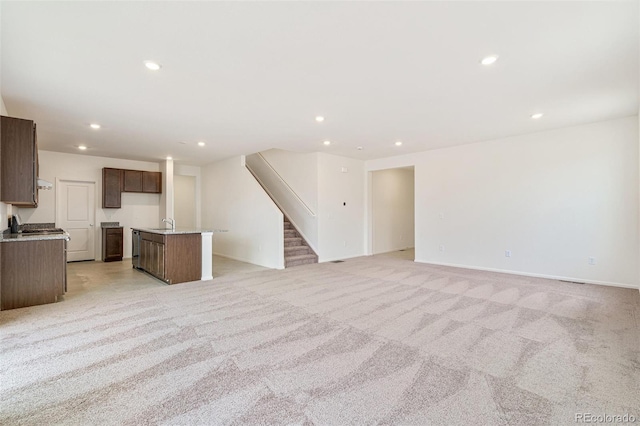 20630 E 58th Ave, Aurora, CO 80019 - unfurnished living room featuring light colored carpet, recessed lighting, stairway, baseboards, and a sink