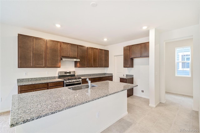 20630 E 58th Ave, Aurora, CO 80019 - kitchen featuring stainless steel gas range, under cabinet range hood, a sink, light stone countertops, and baseboards