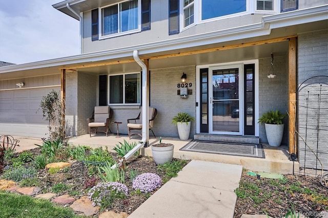 entrance to property featuring covered porch and brick siding