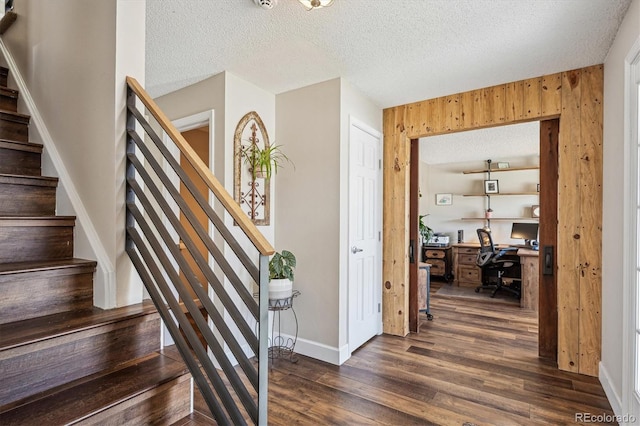 interior space featuring a textured ceiling, baseboards, wood walls, and wood finished floors