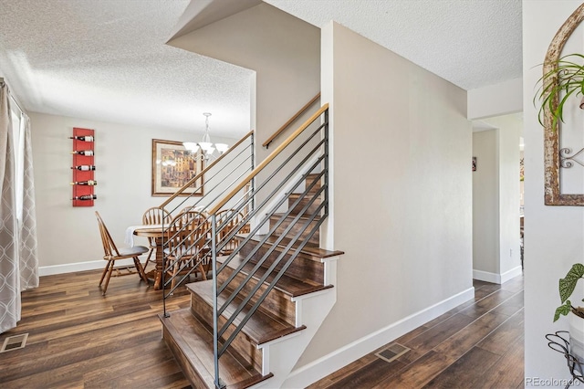 stairs featuring wood finished floors, baseboards, a textured ceiling, and visible vents