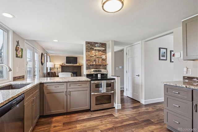 kitchen featuring dark wood-style flooring, light stone counters, a sink, gray cabinets, and stainless steel appliances