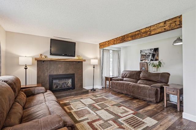 living area featuring a glass covered fireplace, baseboards, a textured ceiling, and wood finished floors
