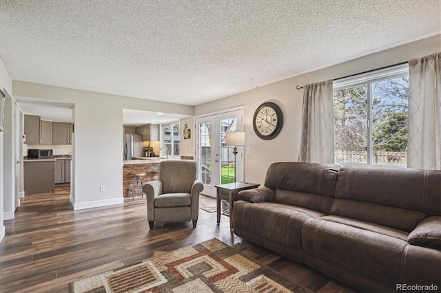 living room featuring a textured ceiling, dark wood-style floors, and baseboards