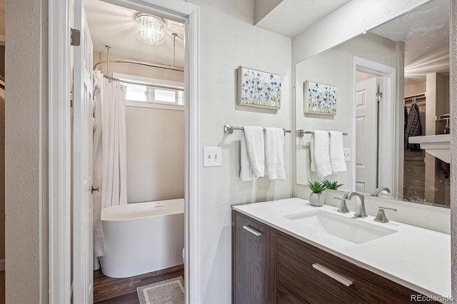 full bath with a freestanding tub, wood finished floors, vanity, a spacious closet, and a shower with shower curtain