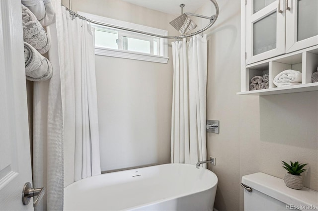 full bath featuring toilet, a freestanding tub, and a shower with shower curtain