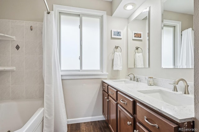 bathroom featuring a sink, shower / bath combo with shower curtain, double vanity, and wood finished floors