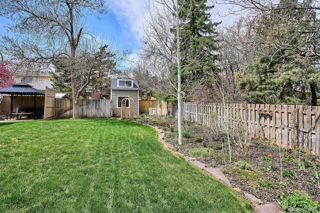 view of yard featuring a gazebo, an outbuilding, a fenced backyard, and a storage unit