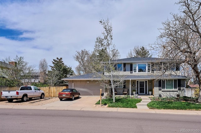 traditional-style home featuring fence, a porch, an attached garage, and driveway