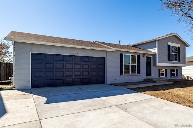 split level home with driveway, brick siding, an attached garage, and fence