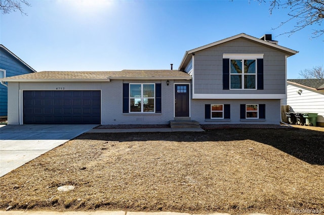 tri-level home with an attached garage, concrete driveway, and brick siding