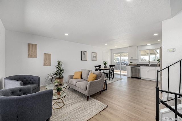 living room with stairs, a textured ceiling, light wood-type flooring, and recessed lighting