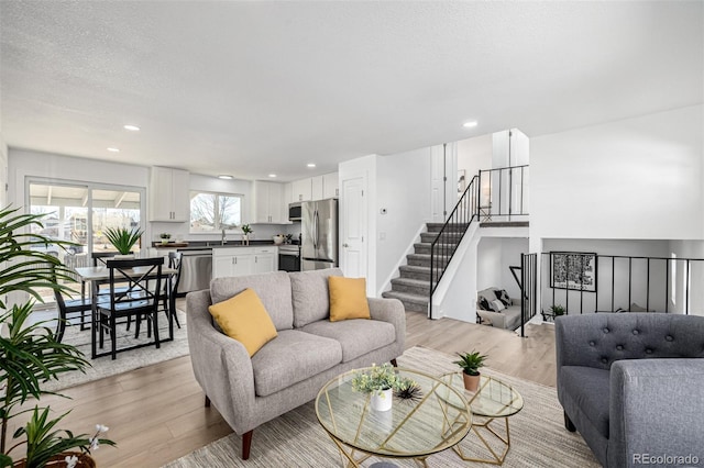 living area featuring a textured ceiling, stairway, light wood-type flooring, and recessed lighting