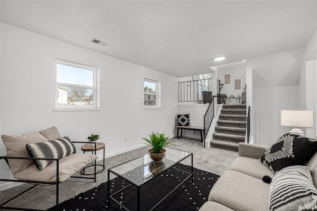 living room with stairway, carpet, visible vents, and baseboards