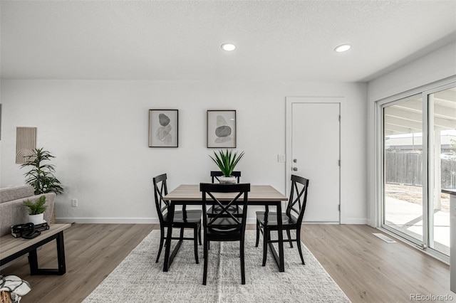 dining area featuring baseboards, wood finished floors, and recessed lighting